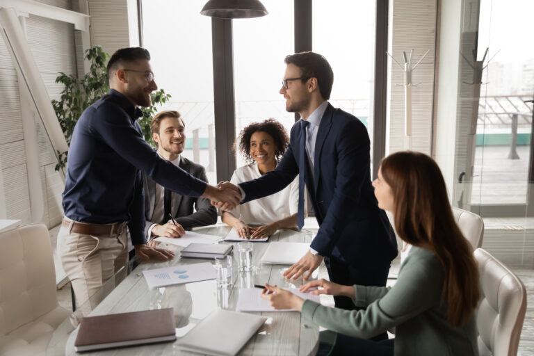 Two male confident partners shaking hands, establishing profitable cooperation.
