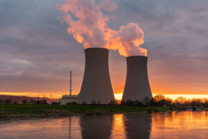 Nuclear power plant against sky by the river at sunset