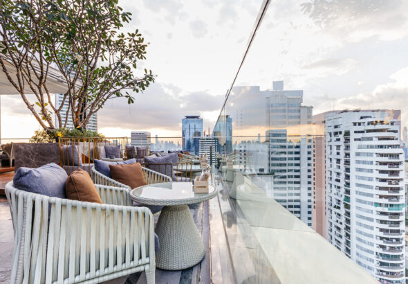 Outdoor rooftop bar with outdoor sofa sets in the evening. This space can take a view of modern buildings in Bangkok.