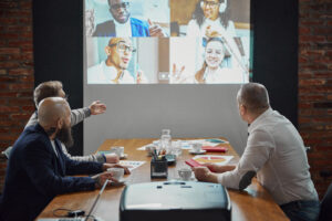 Group of employees, projects managers having online video call on tv screen monitor in conference room. Project discussion with team