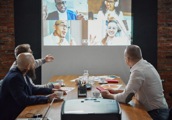 Group of employees, projects managers having online video call on tv screen monitor in conference room. Project discussion with team