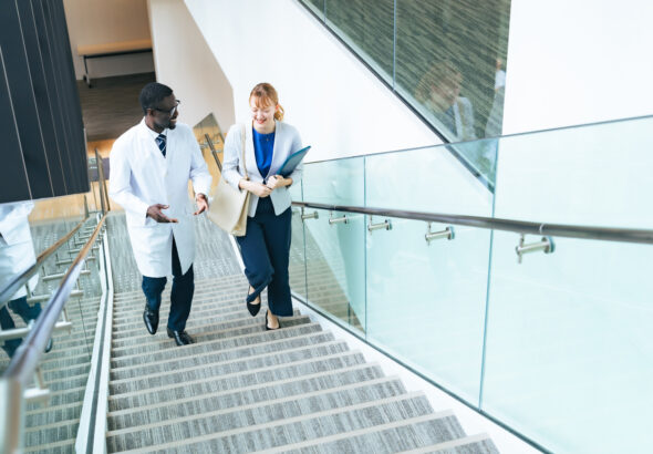 A researcher in a white coat and a female business person having a conversation in an office