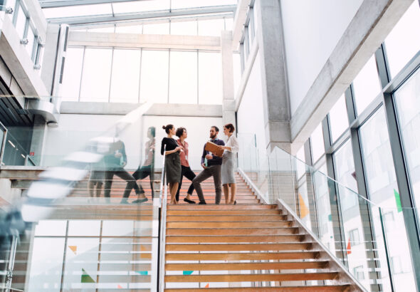 Group of young businesspeople standing on a staircase, talking.
